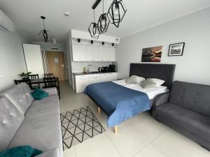 sypialnia z łóżkiem i kanapą w obiekcie Kasprowicza 20 Luxury Apartments - Free Pool, Saunas, Salzgrotte, Jacuzzi, Gym, Children's Playroom, Fitness w Kołobrzegu +37 zdjęć