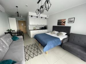 sypialnia z łóżkiem i kanapą w obiekcie Kasprowicza 20 Luxury Apartments - Free Pool, Saunas, Salzgrotte, Jacuzzi, Gym, Children's Playroom, Fitness w Kołobrzegu