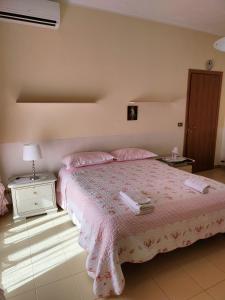 een slaapkamer met een bed met roze lakens en roze kussens bij Appartamento in villa Virginia in Mondragone