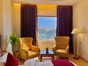 una habitación de hotel con 2 sillas y una ventana en Hotel Gange, Haridwar, en Haridwar