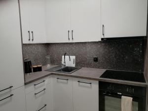 a kitchen with white cabinets and a sink at Apartament Mielczarskiego in Elblag