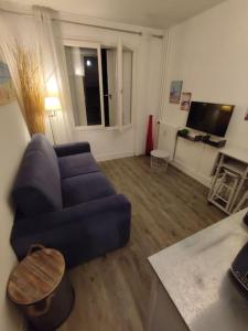 a living room with a blue couch and a table at Studio - Phalènes proche CID in Deauville +6 photos