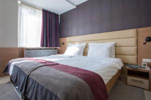 una camera da letto con un grande letto con lenzuola bianche di Hotel Srbija Garden Ex Garni a Belgrado