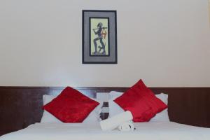 a bed with red pillows and a picture on the wall at Mawuya Lodge in Victoria Falls
