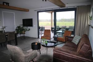 een woonkamer met een bank, stoelen en een tafel bij Vakantiehuis Buitenhuis c in Biezenmortel