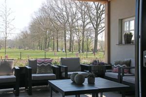 un patio con sillas y mesas y vistas a un parque en Vakantiehuis Buitenhuis c, en Biezenmortel