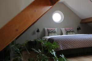 een slaapkamer op zolder met een bed en een raam bij Vakantiehuis Buitenhuis c in Biezenmortel