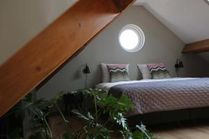 a attic bedroom with a bed and a window at Vrijstaand vakantiehuis Weideblik in Biezenmortel