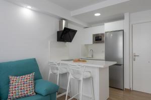 Petit Accommodation Las Canteras Deuxième في لاس بالماس دي غران كاناريا: مطبخ مع كونتر وأريكة زرقاء في غرفة