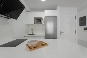 Petit Accommodation Las Canteras Deuxième في لاس بالماس دي غران كاناريا: مطبخ أبيض مع حوض ووعاء على طاولة +12 صورة