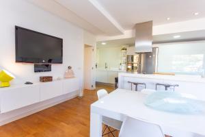 a kitchen with a white table and a tv on a wall at Cullera Beach Apartment Cap Blanc in Cullera