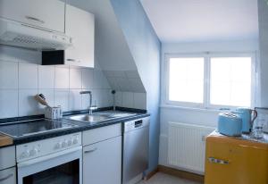una cucina con mobili bianchi, un lavandino e una finestra di Villa Kunterbunt - sehr zentral, neu renoviert, 2SZ a Wangen im Allgäu