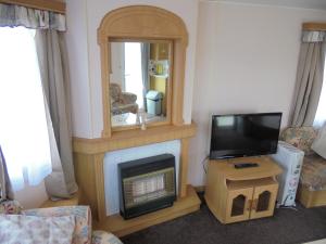 a living room with a fireplace and a tv at 8 Berth on Coastfields (Everglade) in Ingoldmells