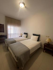 2 łóżka w pokoju hotelowym z oknem w obiekcie Fátima GuestHouse w Fatimie