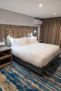 a bedroom with a large white bed and a table at Zar in Amanzimtoti