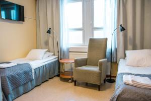 um quarto com duas camas e uma cadeira e uma janela em Hotelli Sointula em Orivesi