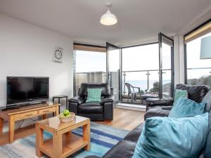 a living room with a couch and chairs and a tv at Cove View in Porthcurno