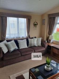 a living room with a brown couch with white pillows at Slatersaunders56 in Meliden