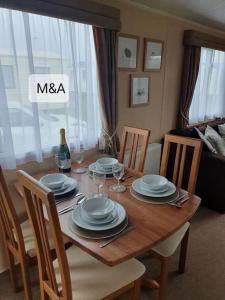 a wooden table with plates and wine glasses on it at Slatersaunders56 in Meliden