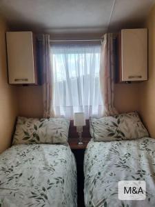 two beds in a small bedroom with a window at Slatersaunders56 in Meliden