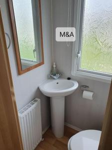 a bathroom with a sink and a toilet and a mirror at Slatersaunders56 in Meliden