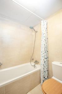 a bathroom with a bath tub and a toilet at Modern studio apartment in the heart of St Julians in St. Julianʼs