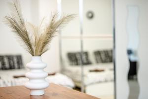 a white vase with feathers in it on a table at Modern studio apartment in the heart of St Julians in St. Julianʼs