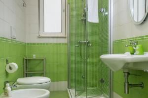 a green tiled bathroom with a toilet and a sink at Aurora Sul Mare in Otranto