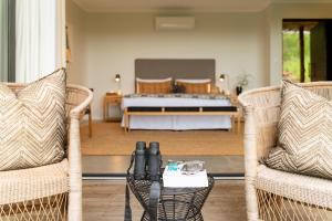- une chambre avec un lit, deux chaises et une table dans l'établissement Sungulwane Private Game Lodge, à Hluhluwe