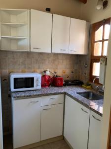a kitchen with white cabinets and a microwave on a counter at Amplio departamento monoambiente a metros del parque general San Martín in Mendoza +6 photos