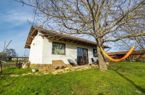 ein Haus mit einem Baum und einer Hängematte davor in der Unterkunft Вила "Намасте" с панорамна гледка и камина на дърва in Lovech