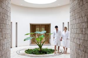 two people in white robes standing next to a plant at Hyatt Zilara Riviera Maya Adults Only All-Inclusive in Playa del Carmen