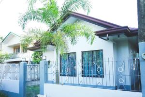 a house with a blue fence and palm trees at CosiHome Guesthouse in Laguna