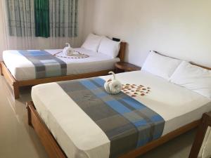 two beds in a bedroom with two birds sitting on them at Shan Guest and Restaurant Nilaveli in Trincomalee