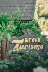 a sign for a hotel in a garden at Hotel Turismo in San Martín de los Andes