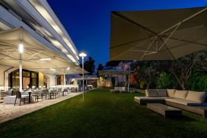 un patio al aire libre con mesas y sombrillas por la noche en Vittoria Resort Pool & SPA, en Otranto