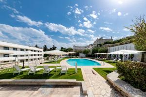 un complejo con piscina, sillas y sombrillas en Vittoria Resort Pool & SPA, en Otranto