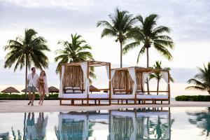 a couple walking by the pool at a resort at Hyatt Zilara Riviera Maya Adults Only All-Inclusive in Playa del Carmen