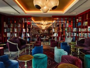 uma biblioteca com cadeiras, mesas e estantes em 25hours Hotel The Royal Bavarian em Munique