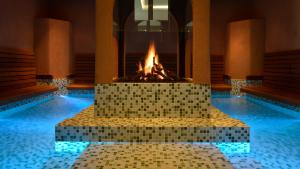 a swimming pool with a fireplace in the middle at Essensio Hotel Düsseldorf in Erkrath