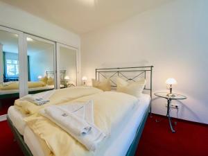 a bedroom with a large white bed with a mirror at Haus Kastell - Suite Strandglück in Ahlbeck