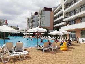 una piscina con tumbonas, sombrillas y personas nadando en Apartment Daisy Grand Kamelia en Sunny Beach