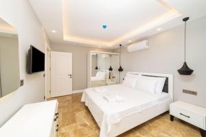 a white bedroom with a white bed and a mirror at Fully Furnished Flat with Sea View in Kas Antalya in Kas