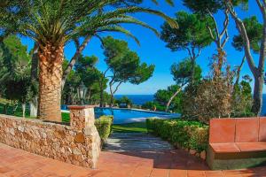 a resort with a bench and palm trees and a pool at Club Villamar - El Far in Llafranc