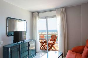 ein Wohnzimmer mit einem TV und Strandblick in der Unterkunft Club Villamar - Apartment Amatella in Sant Antoni de Calonge