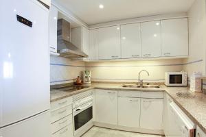 eine weiße Küche mit einer Spüle und einem Kühlschrank in der Unterkunft Club Villamar - Apartment Amatella in Sant Antoni de Calonge