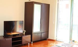 a living room with a tv and a brown cabinet at Lemon Hill in Herceg-Novi