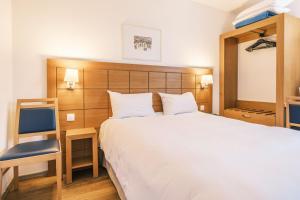 1 dormitorio con 1 cama blanca grande y 1 silla en Hotel Strasbourg - Montagne Verte & Restaurant Louisiane en Estrasburgo