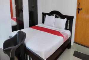 ein Schlafzimmer mit einem Bett und einem Stuhl in einem Zimmer in der Unterkunft STAYMAKER Anjaneya Comforts in Shimoga
