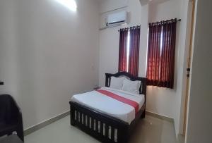 a small bedroom with a bed with red curtains at STAYMAKER Anjaneya Comforts in Shimoga